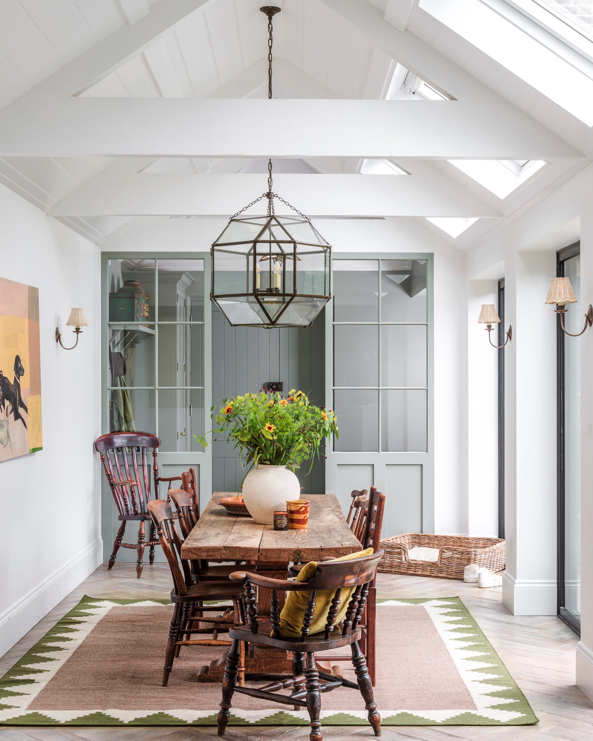 Bright dining area featuring a rustic wooden table, vintage spindle-back chairs, and a geometric glass pendant light