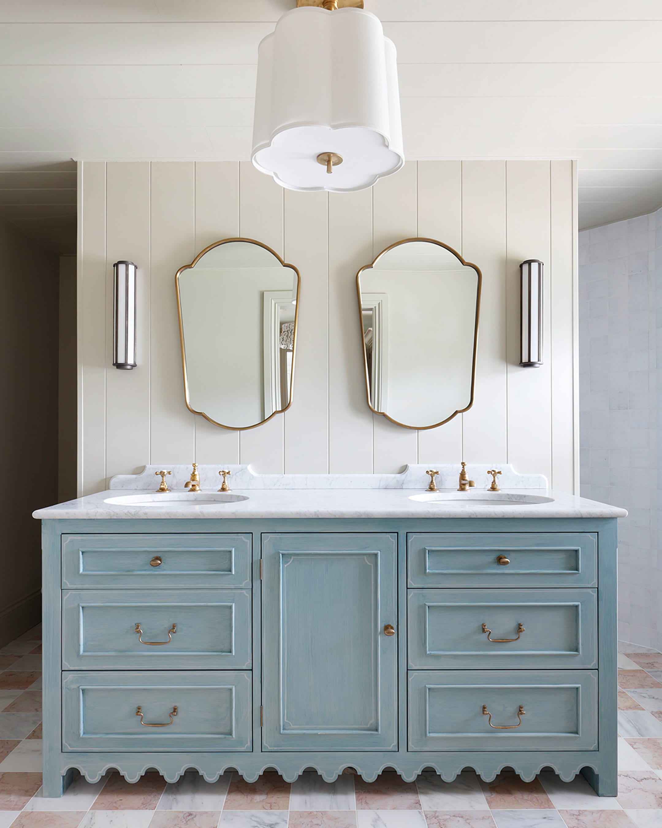 Bathroom featuring a pale blue vanity with scalloped edges, white marble countertop, and gold fixtures against soft beige paneling