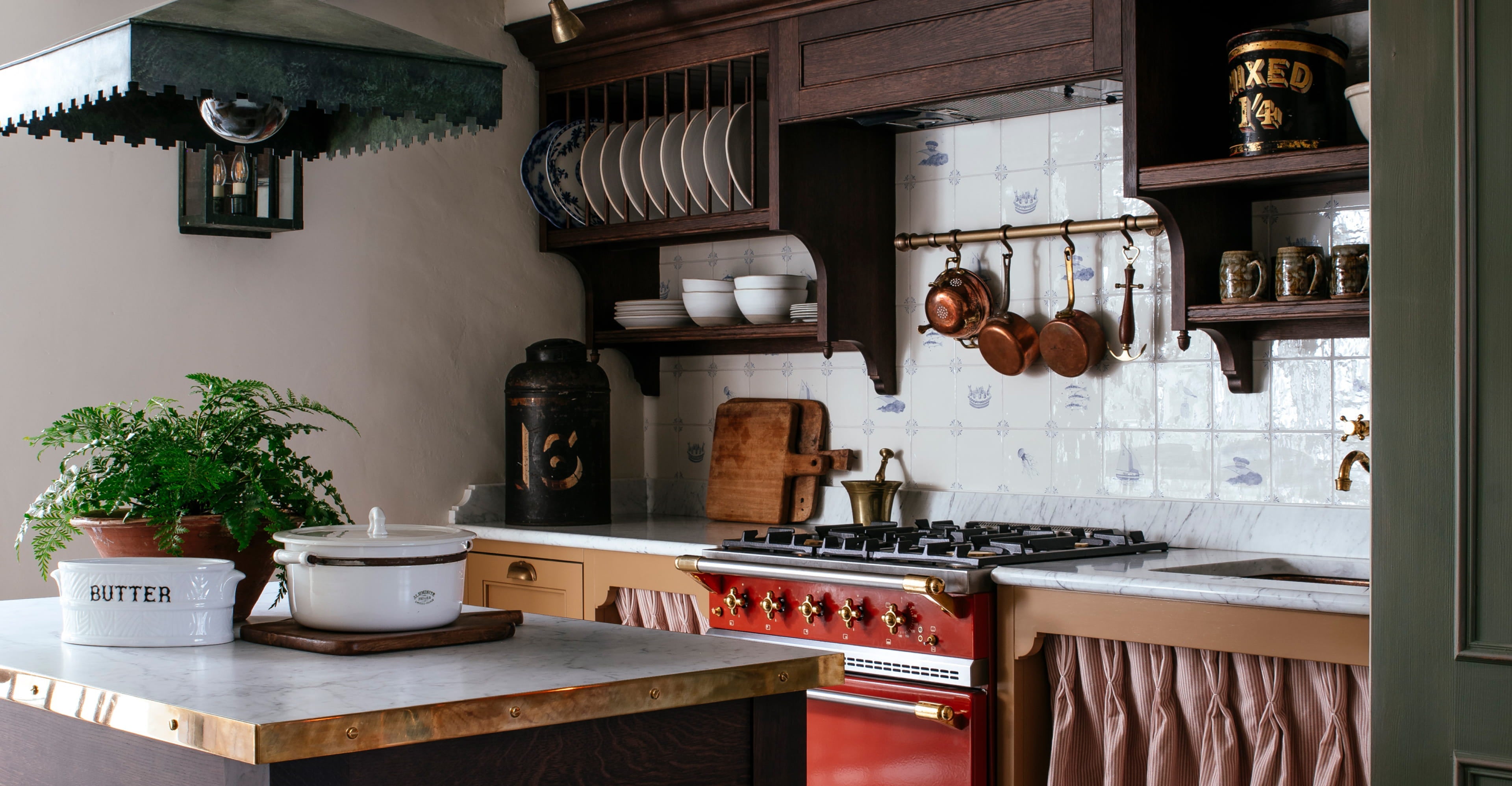 Kitchen featuring a brass range cooker, white ceramic dishware, and dark oak cabinetry with a vintage copper pot collection