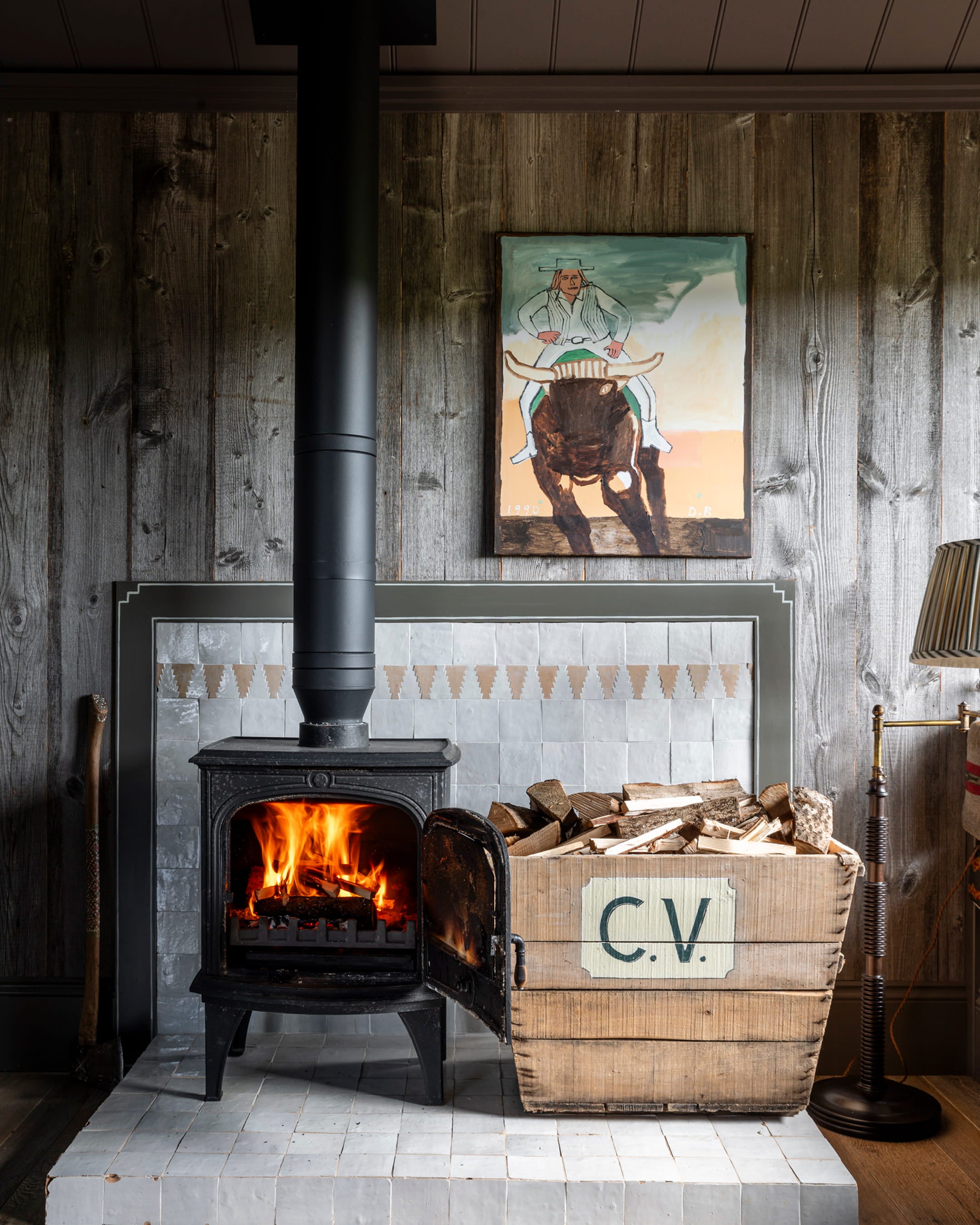 Cozy living space featuring a black wood-burning stove, reclaimed wood paneling, and a vibrant artwork above the fireplace