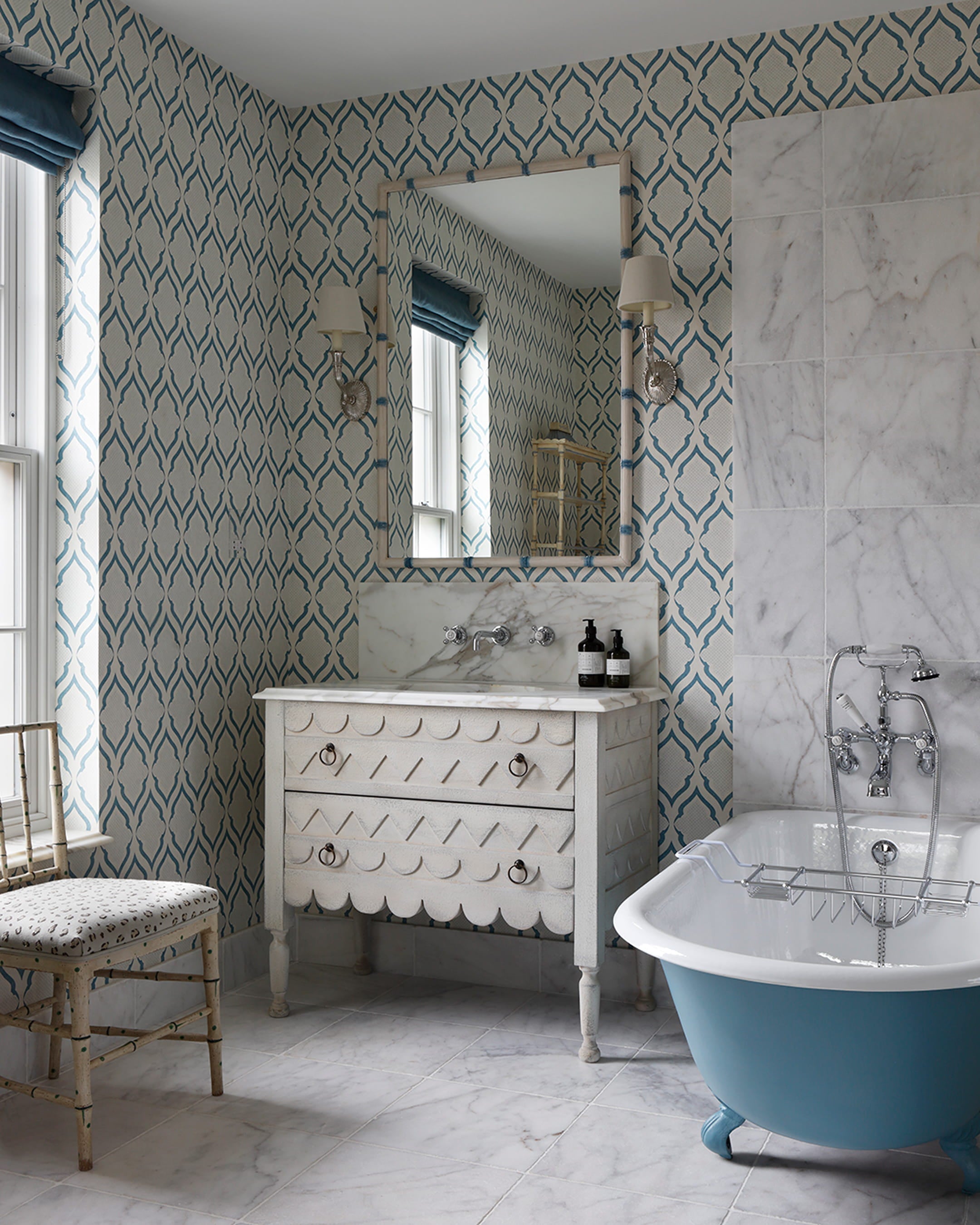Bathroom featuring patterned blue and white wallpaper, a scalloped white vanity, and a freestanding tub with a turquoise base