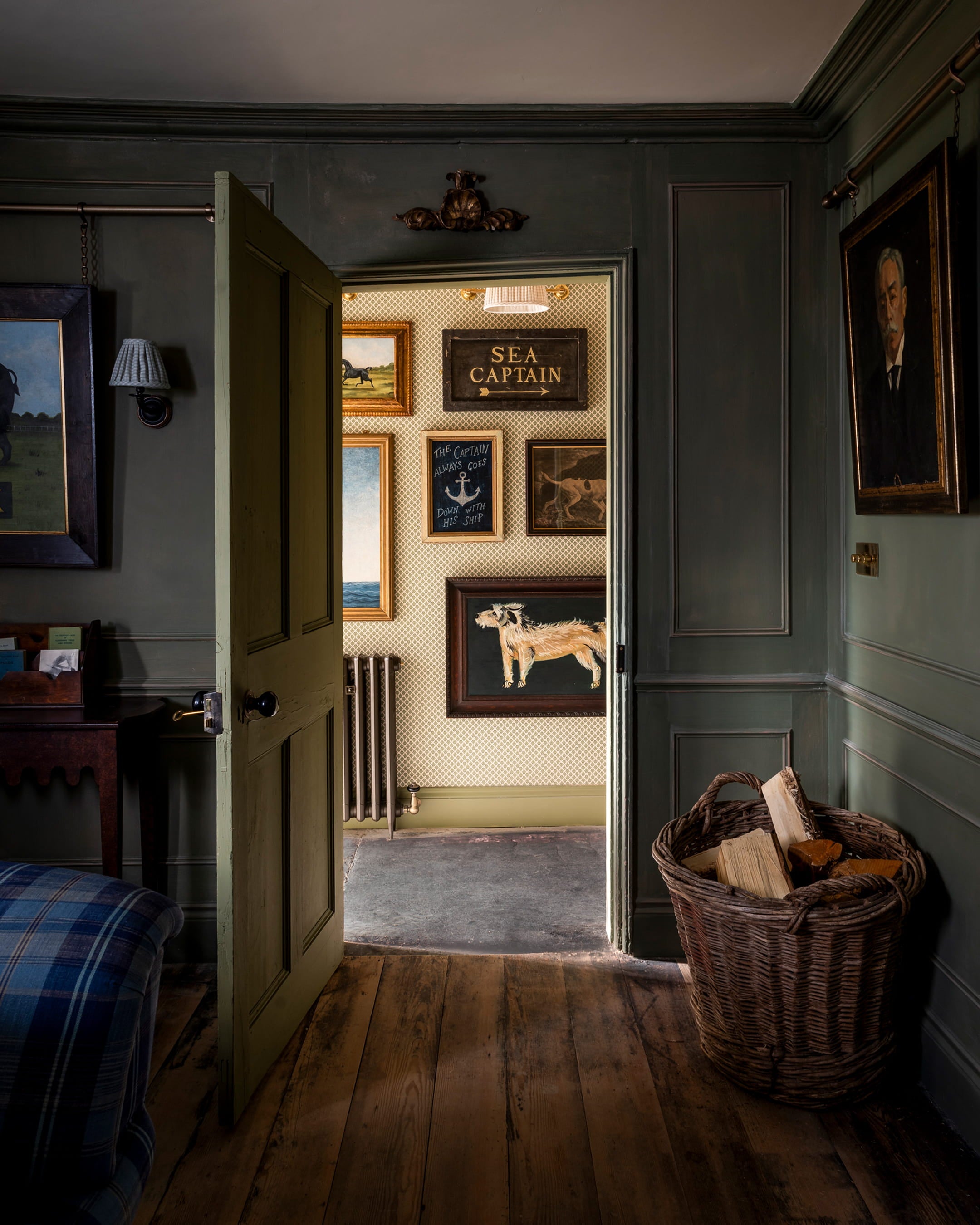 Entryway featuring deep green paneling, a vintage wooden chair, and a collection of framed maritime artwork on the wall