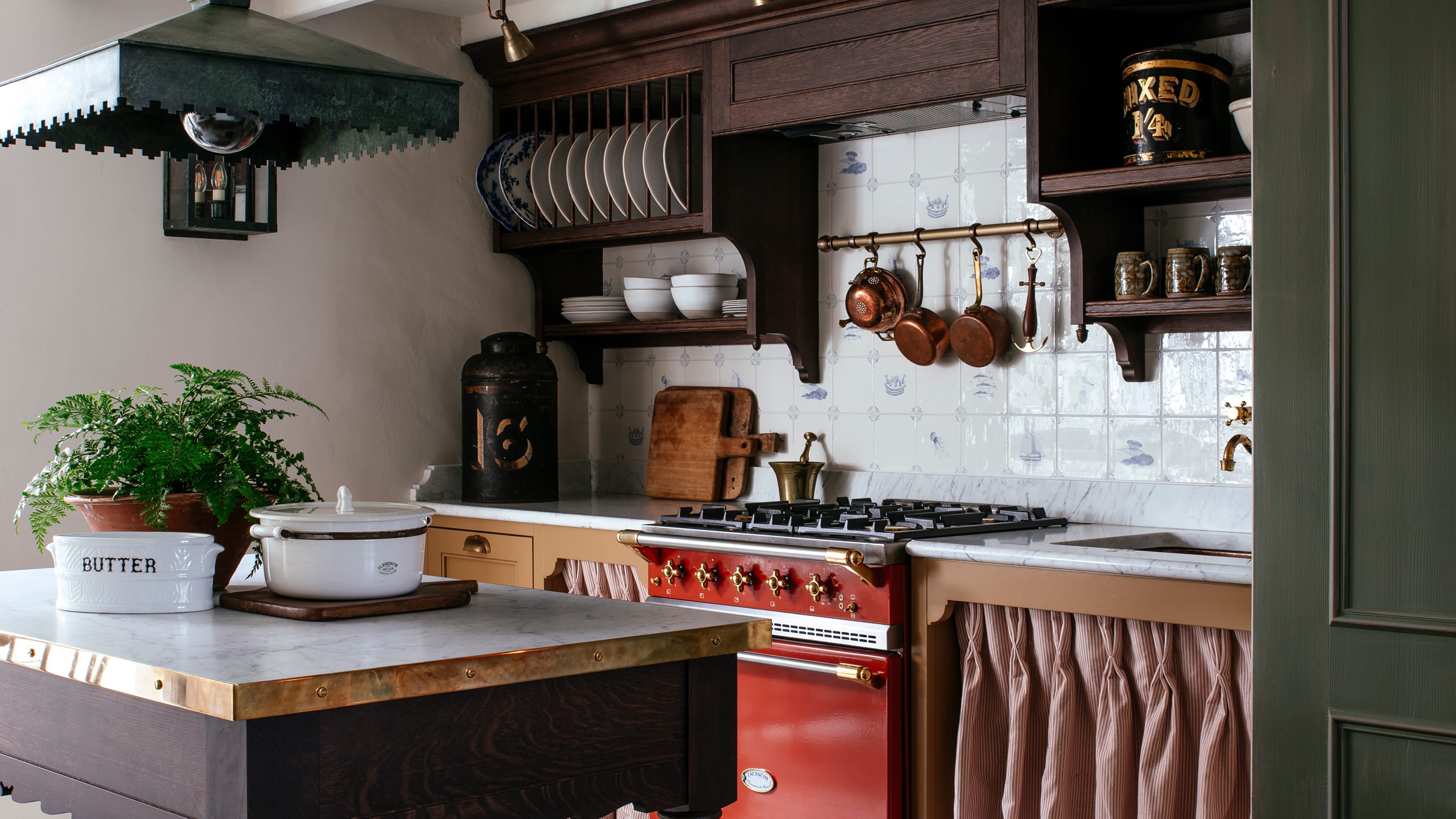 Kitchen featuring a brass range cooker, white ceramic dishware, and dark oak cabinetry with a vintage copper pot collection