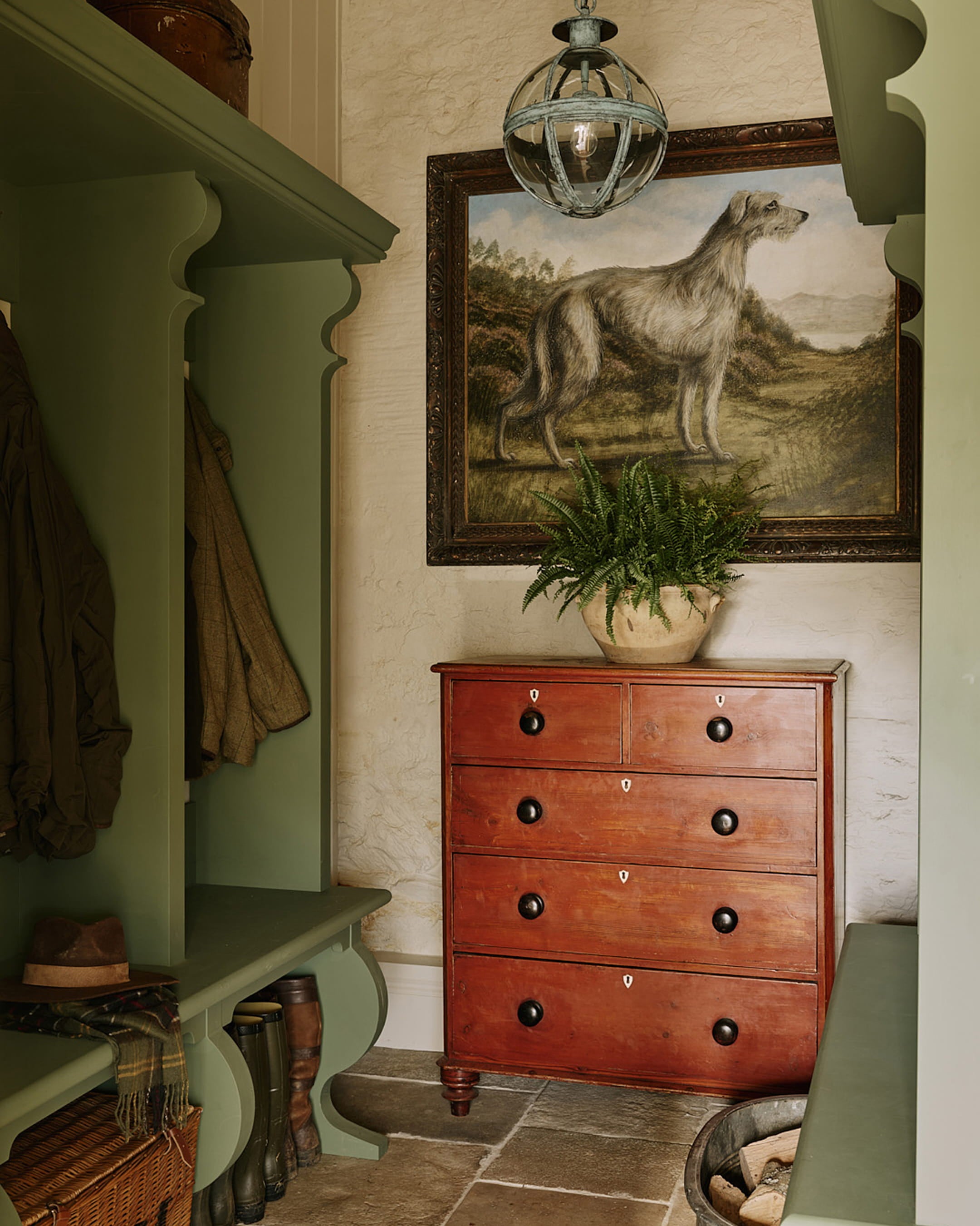 Mudroom featuring olive green cabinetry, a rustic red chest of drawers, and a vintage dog painting on the wall