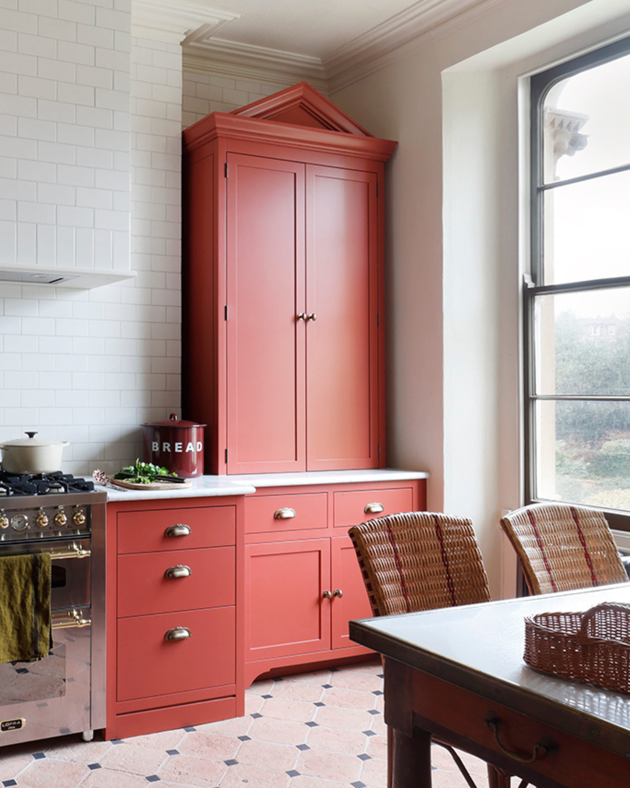 Kitchen featuring a bold terracotta cabinet, white subway tile backsplash, and a vintage-style marble countertop