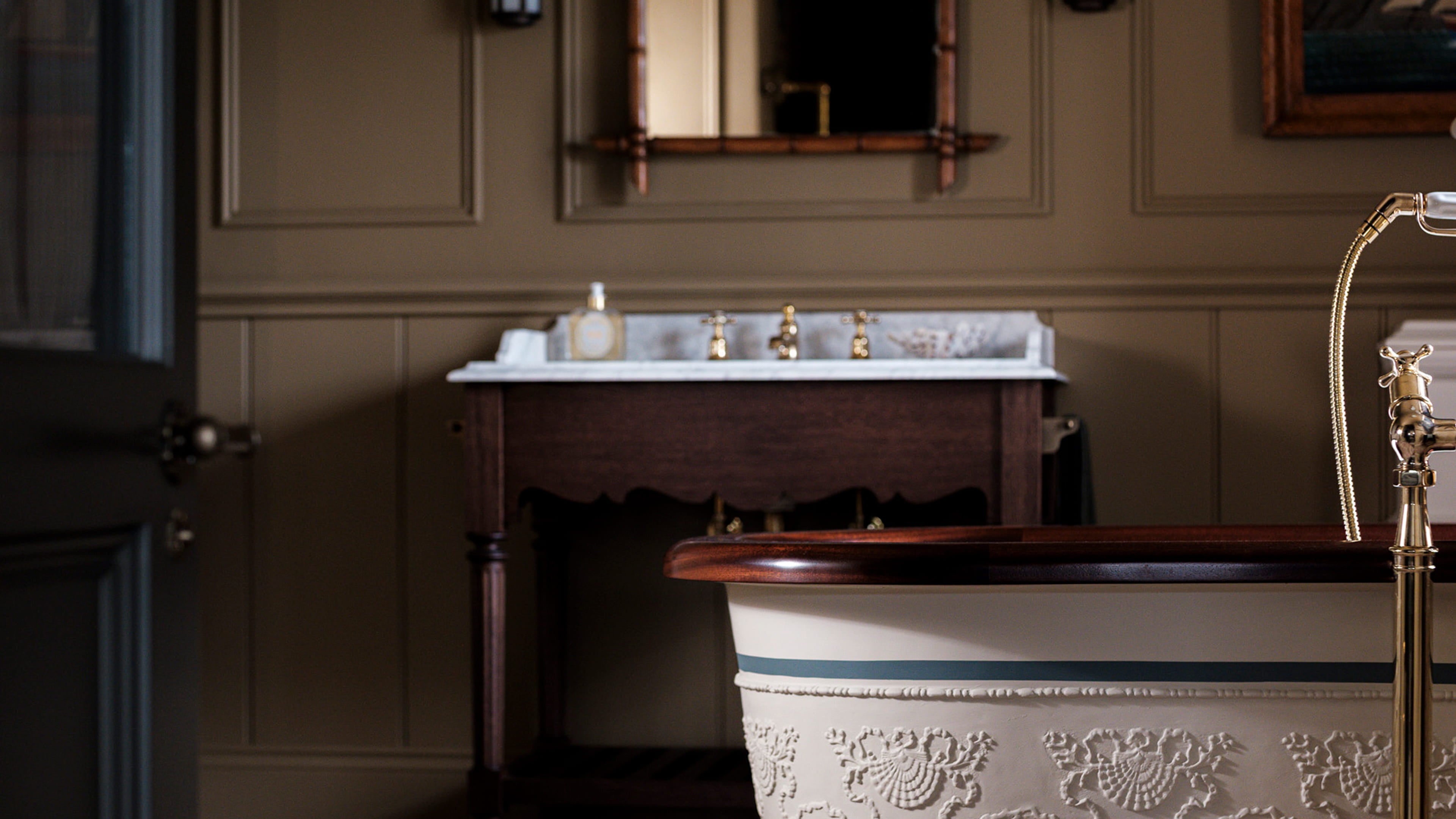 Bathroom featuring a freestanding tub with intricate plaster detailing, a dark walnut vanity, and a marble countertop