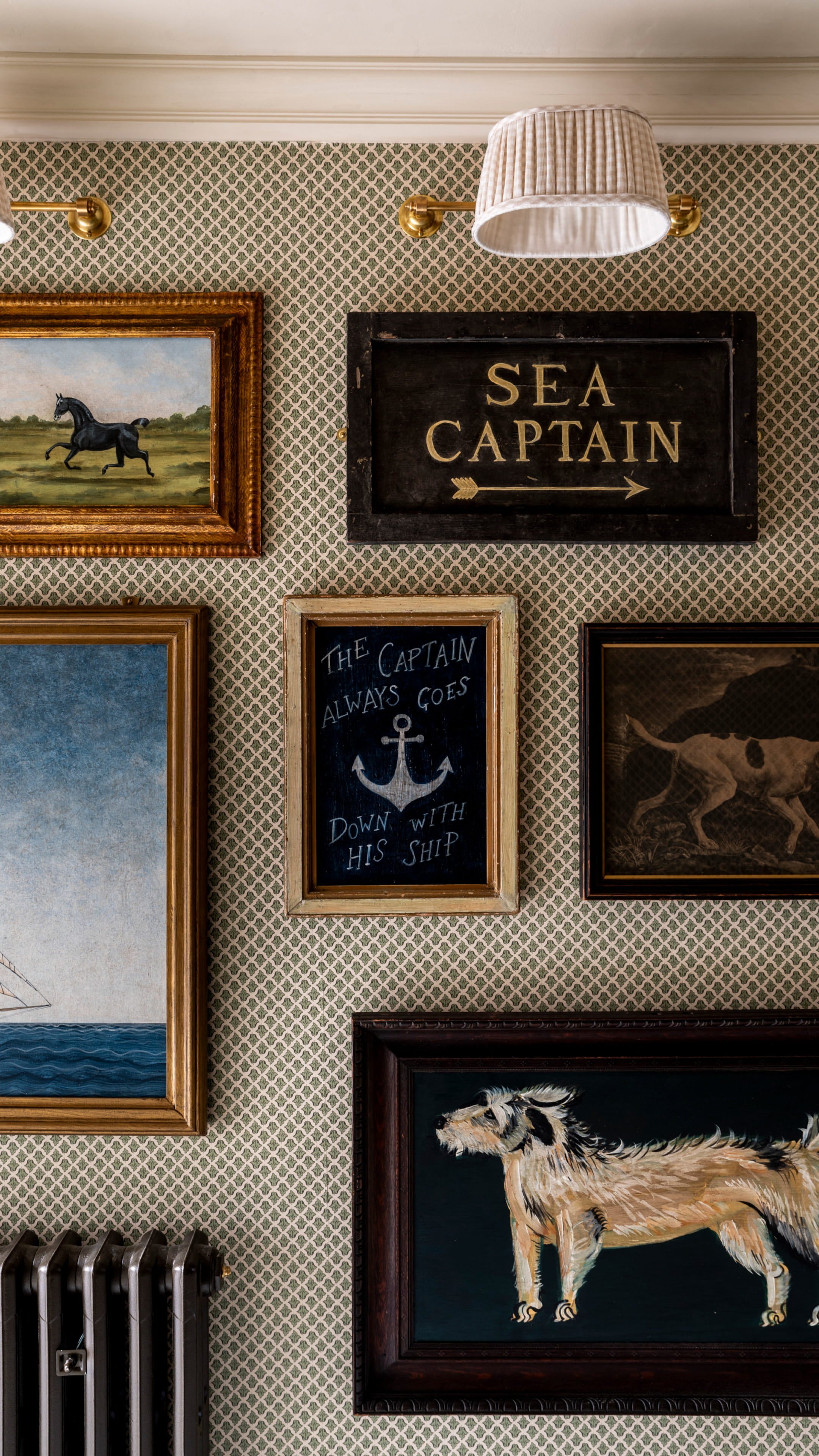 Gallery wall featuring vintage paintings, a chalkboard sign, and a patterned wallpaper in muted green tones
