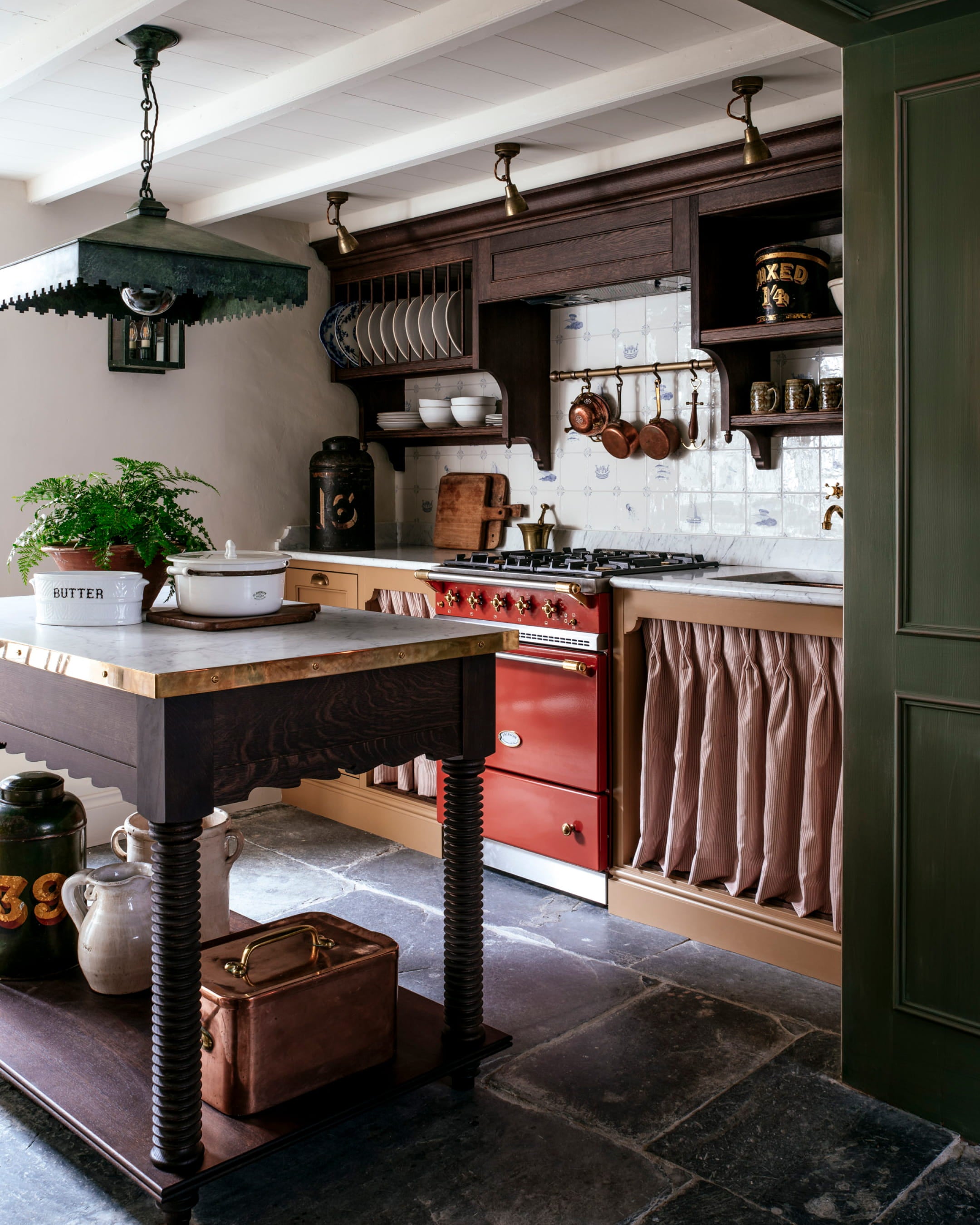 Rustic kitchen featuring a red range cooker, dark walnut cabinetry, a marble countertop, and a vintage metal light fixture