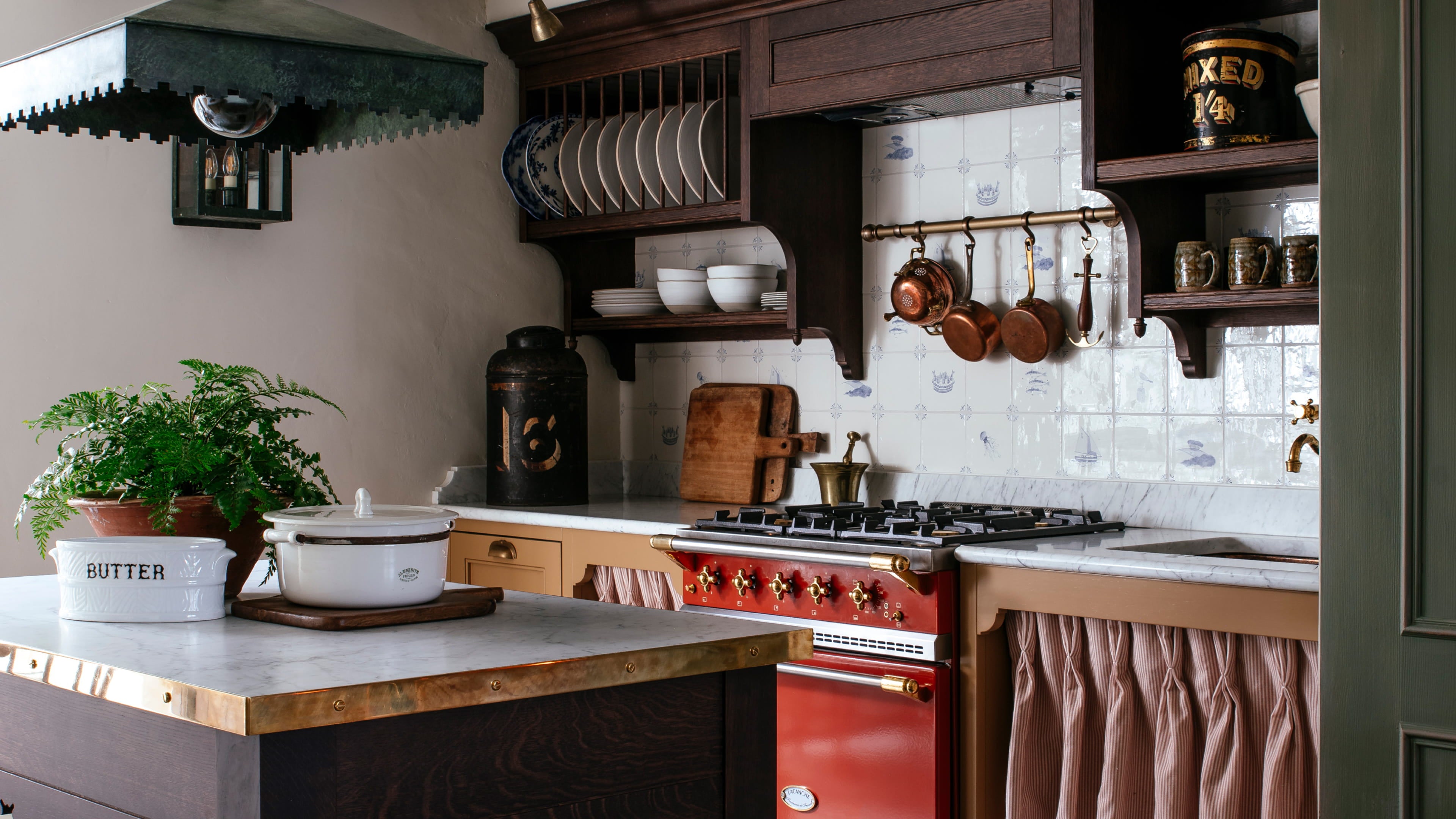 Kitchen featuring a brass range cooker, white ceramic dishware, and dark oak cabinetry with a vintage copper pot collection
