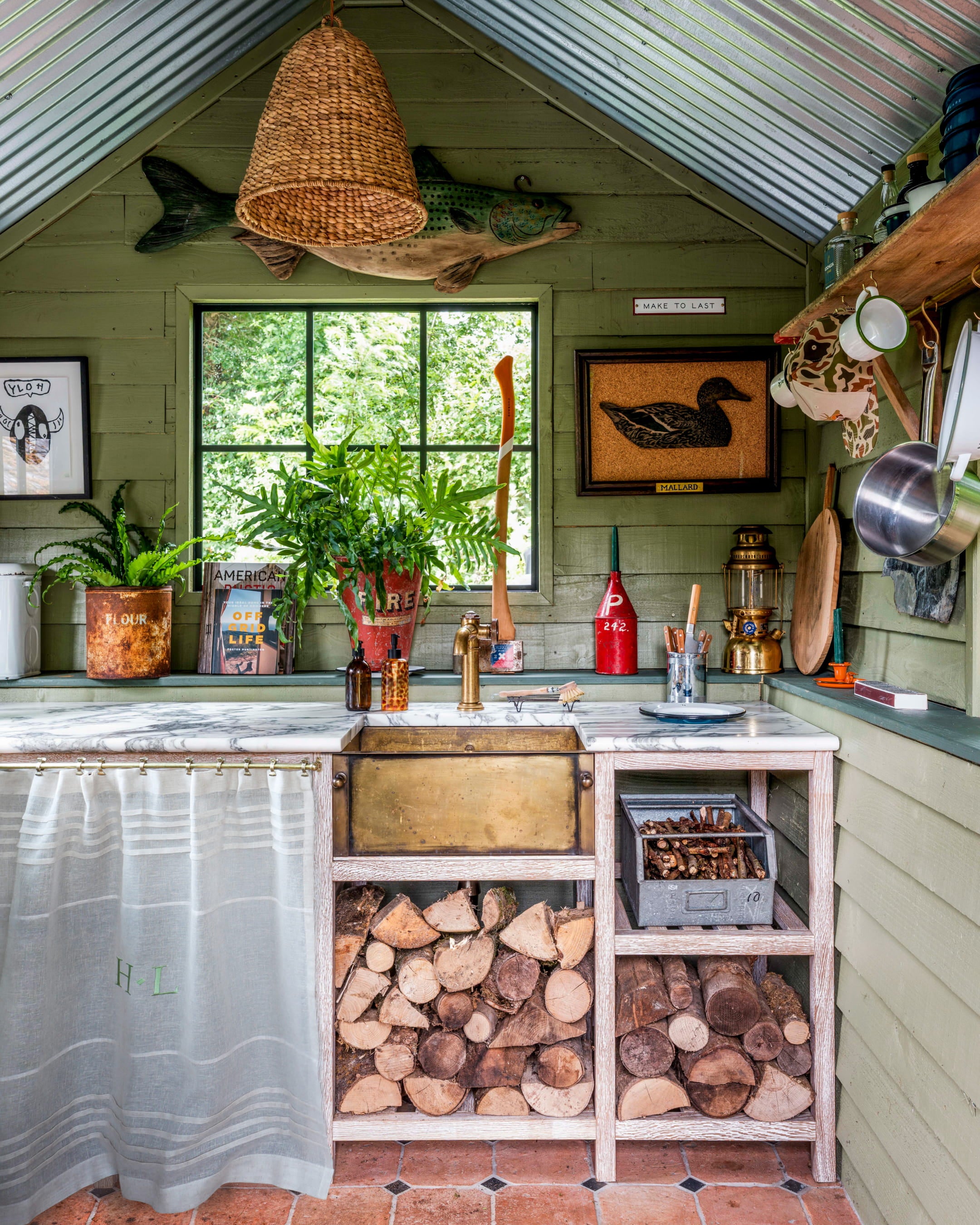 Rustic kitchen featuring green shiplap walls, a marble countertop, brass fixtures, and a woven pendant light above the sink