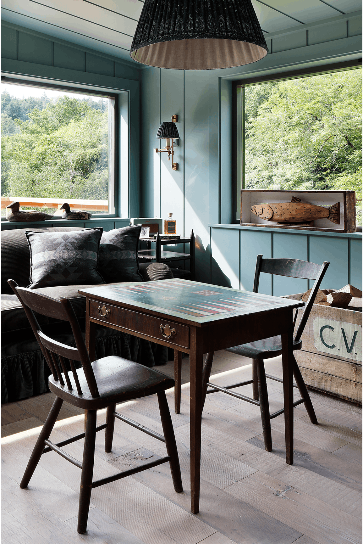 Cozy seating area featuring a dark wood table with a colorful painted top, surrounded by black wooden chairs and plush cushions