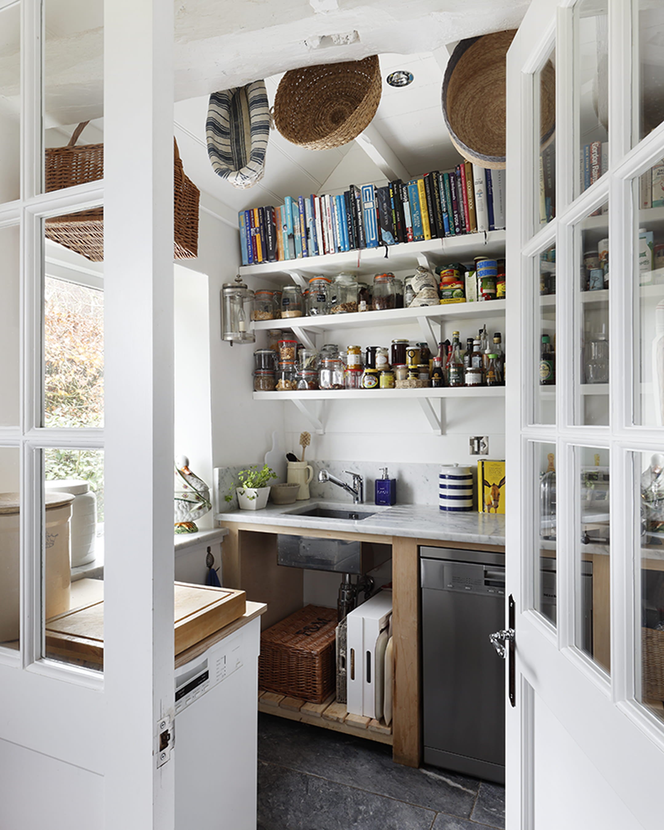 Bright kitchen featuring white shiplap walls, a marble countertop, open shelving with jars, and rustic wooden accents
