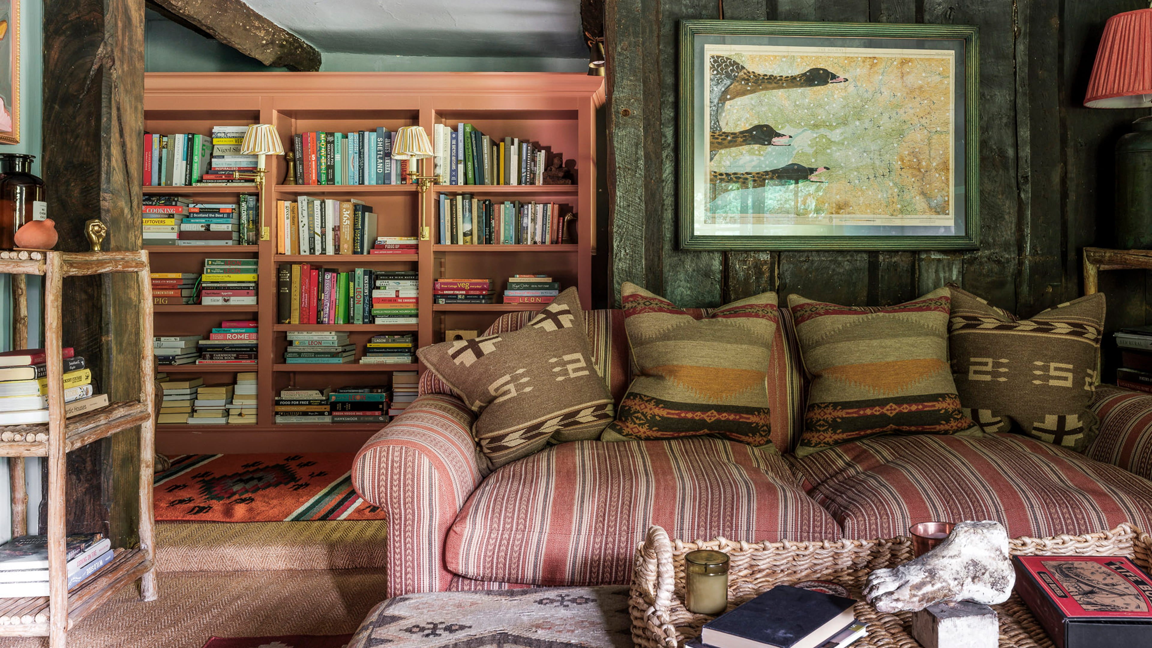 Cozy reading nook featuring a striped sofa with patterned cushions, rustic wooden shelving, and a vibrant tribal rug