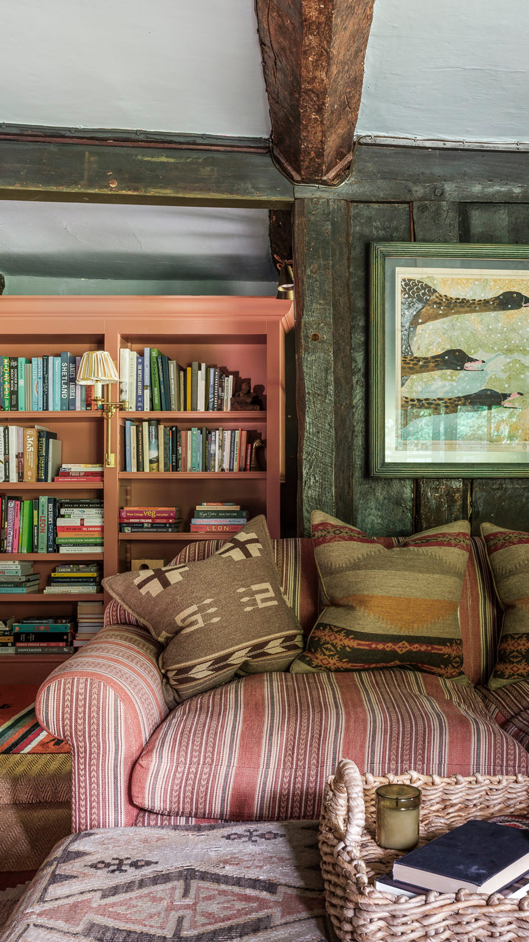 Cozy sitting area featuring a striped fabric sofa, earthy-toned cushions, and a warm terracotta bookcase filled with books