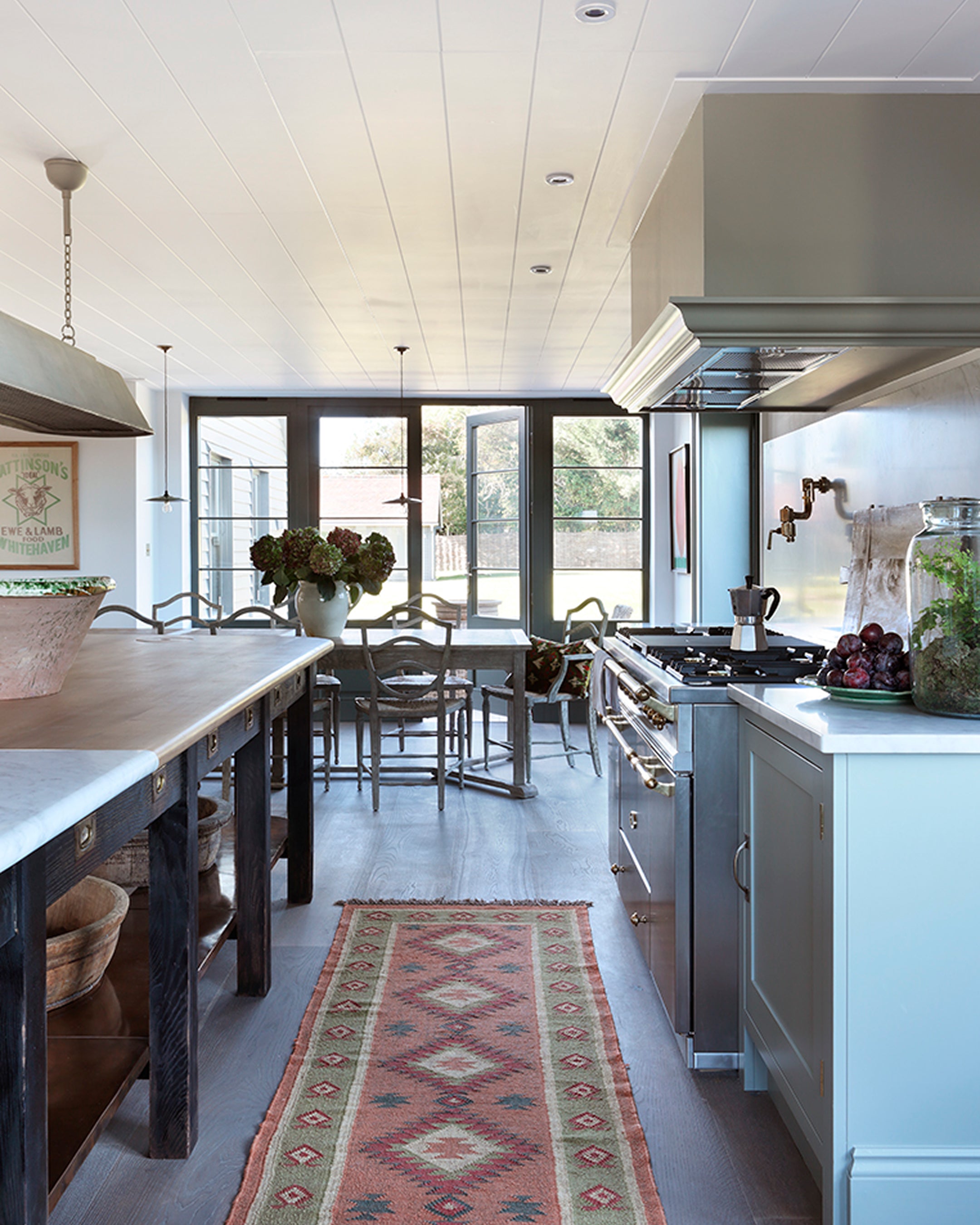 Bright kitchen featuring a white shiplap ceiling, a marble-topped island, and a vintage Persian runner on oak flooring